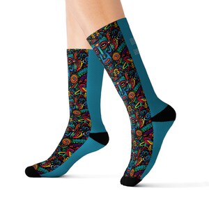 May include: Knee-high socks with a vibrant, colourful pattern featuring abstract faces, suns, and other shapes. The socks have a teal blue background and black accents on the toes and heels. The text "DN" is visible on the side.
