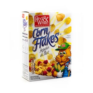 Könnte beinhalten: Eine Schachtel Red & White Corn Flakes-Cerealien. Die Schachtel zeigt eine Cartoon-Katze mit grüner Mütze und Latzhose, die Mais hält. Auf der Schachtel stehen die Worte "Corn Flakes" in blauer Schrift und "Hojuelas de Maíz". Nettogewicht 510g.