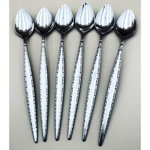 May include: Six stainless steel spoons arranged in a row. The spoons have a teardrop-shaped bowl and a long, slender handle with a decorative pattern. The spoons are reflective, and the image is taken from a top-down perspective.