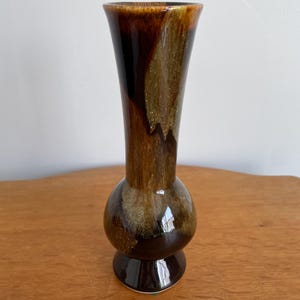 May include: A handmade, ceramic mug with a speckled, cream-colored glaze. The mug features a wide, rounded body and a sturdy handle. The interior is a darker, earthy tone. The mug is approximately 4 inches tall.