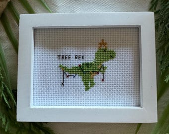 Dibujo de punto de cruz de un T-Rex con un árbol de Navidad