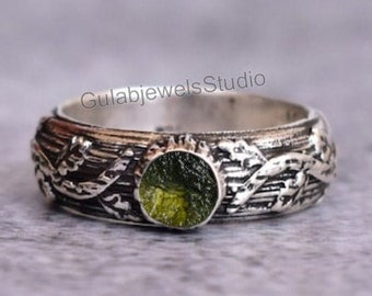 May include: A silver ring with a green gemstone set in a detailed floral design. The ring is made of sterling silver and features a unique, intricate pattern.