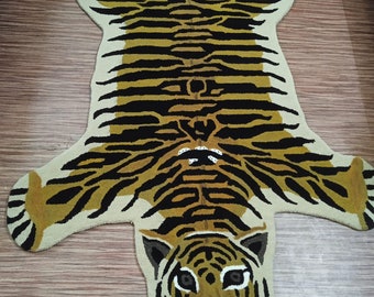May include: A tiger-print rug with a detailed tiger face in the center. The rug is made of a soft, plush material and has a beige and brown color scheme.