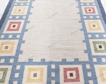 Könnte beinhalten: Ein gewebter Teppich mit einem geometrischen Muster in Blau, Weiß und Rot. Der Teppich hat einen Fransenrand.