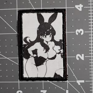 May include: Black and white embroidered patch featuring an anime character with bunny ears wearing a black and white outfit.