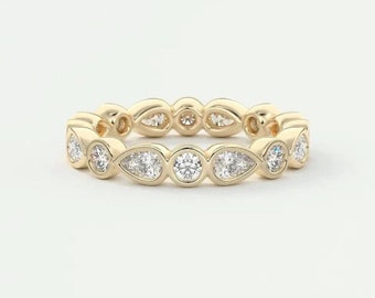 May include: A gold band ring with a row of round and pear-shaped diamonds.