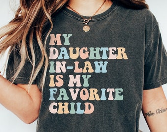 May include: A dark grey t-shirt with the text "My daughter in-law is my favorite child" in colorful letters. The text is in a retro font style.