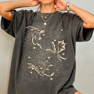 May include: An oversized dark grey t-shirt featuring a graphic print of three dragons flying in a starry sky.