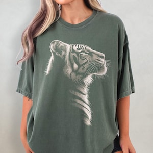 Puede incluir: Una camiseta de gran tama&ntilde;o de color verde oscuro con un gr&aacute;fico blanco de la cabeza de un tigre. El tigre est&aacute; mirando hacia la derecha.