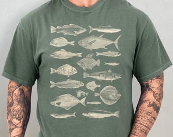 Puede incluir: Una camiseta verde con una ilustración vintage de varios peces impresos en la parte delantera. Los peces son en tonos grises y blancos.