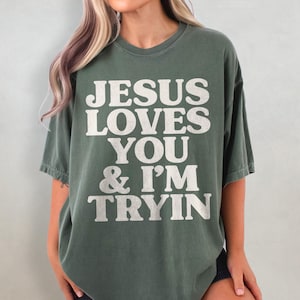 May include: A green oversized t-shirt with the text "JESUS LOVES YOU & I'M TRYIN" in white.