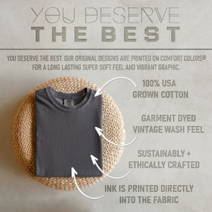 K&ouml;nnte beinhalten: Ein dunkelgraues T-Shirt, das auf einer geflochtenen Matte gefaltet ist. Das T-Shirt besteht aus 100% Baumwolle aus den USA und ist f&uuml;r ein Vintage-Waschgef&uuml;hl gef&auml;rbt. Die Farbe wird direkt in den Stoff gedruckt. Das T-Shirt ist nachhaltig und ethisch hergestellt.