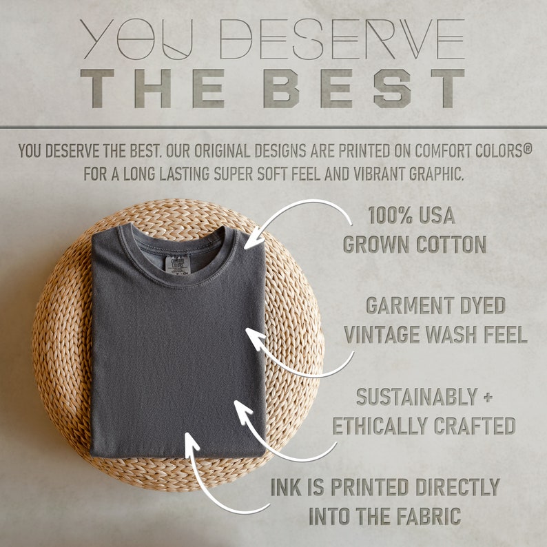 K&ouml;nnte beinhalten: Ein dunkelgraues T-Shirt, das auf einer geflochtenen Matte gefaltet ist. Das T-Shirt besteht aus 100% Baumwolle aus den USA und ist f&uuml;r ein Vintage-Waschgef&uuml;hl gef&auml;rbt. Die Farbe wird direkt in den Stoff gedruckt. Das T-Shirt ist nachhaltig und ethisch hergestellt.