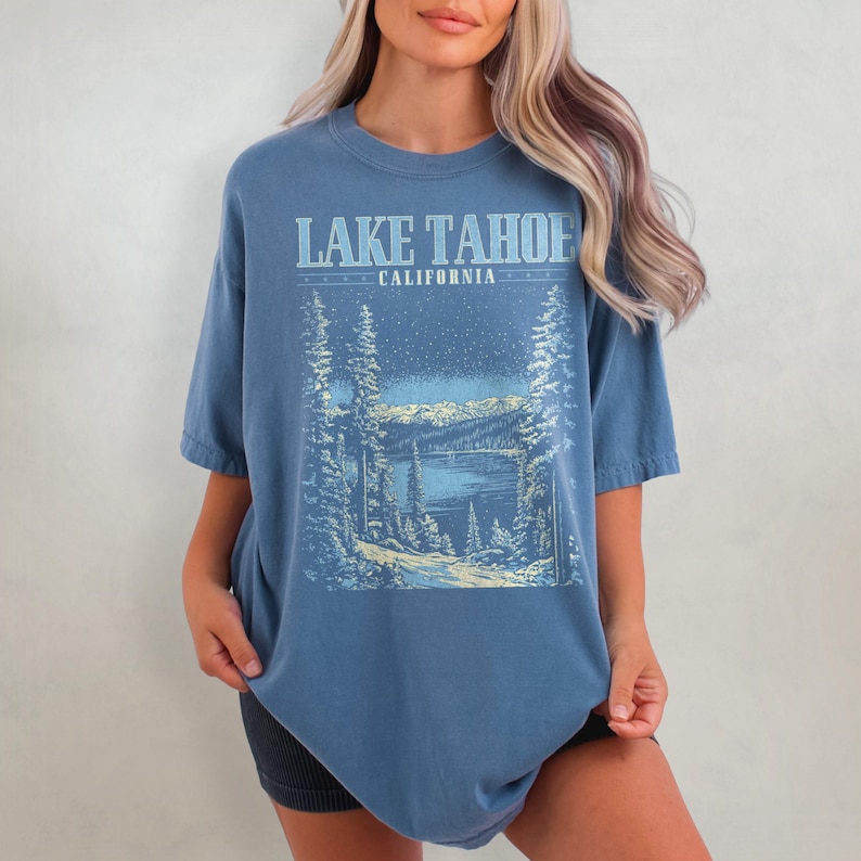 May include: A blue oversized t-shirt with a graphic print of a snowy mountain scene and the text "LAKE TAHOE CALIFORNIA".