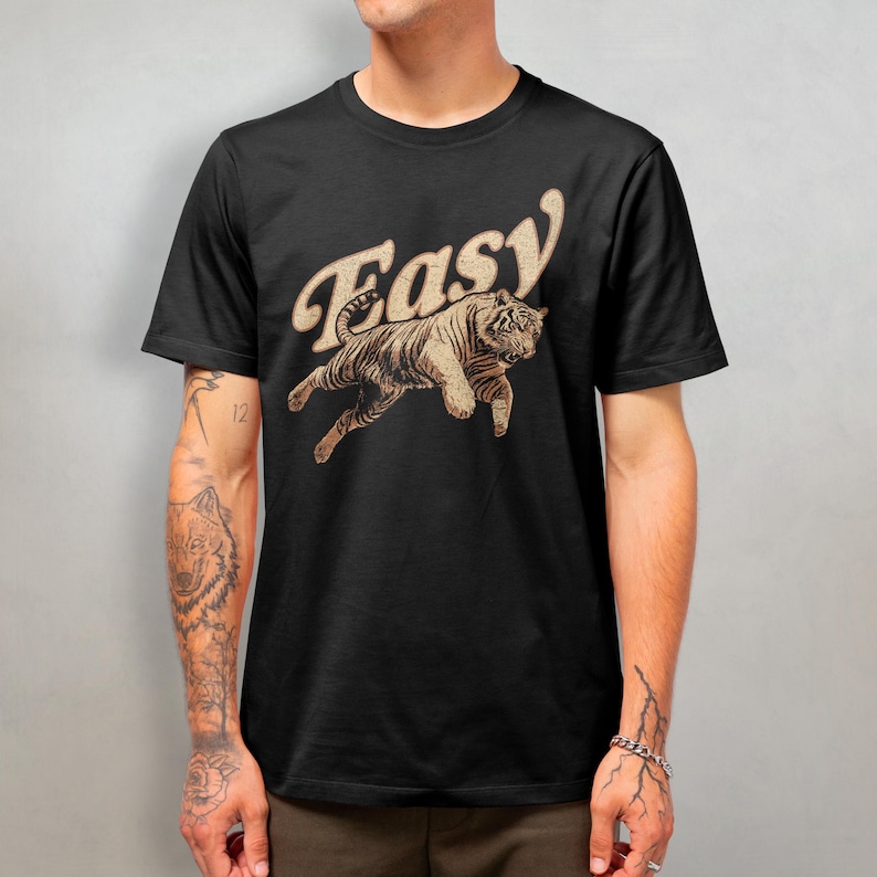Peut inclure: T-shirt noir avec un graphique vintage d'un tigre sautant avec le mot "Easy" dans une police r&eacute;tro.