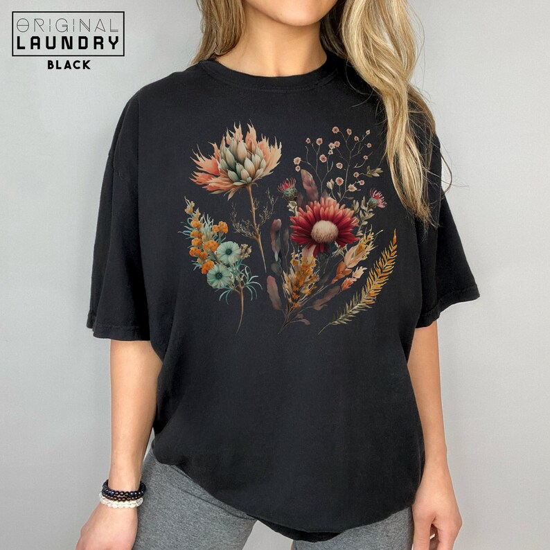 May include: A black t-shirt with a floral print featuring a variety of flowers in shades of red, orange, yellow, and blue.