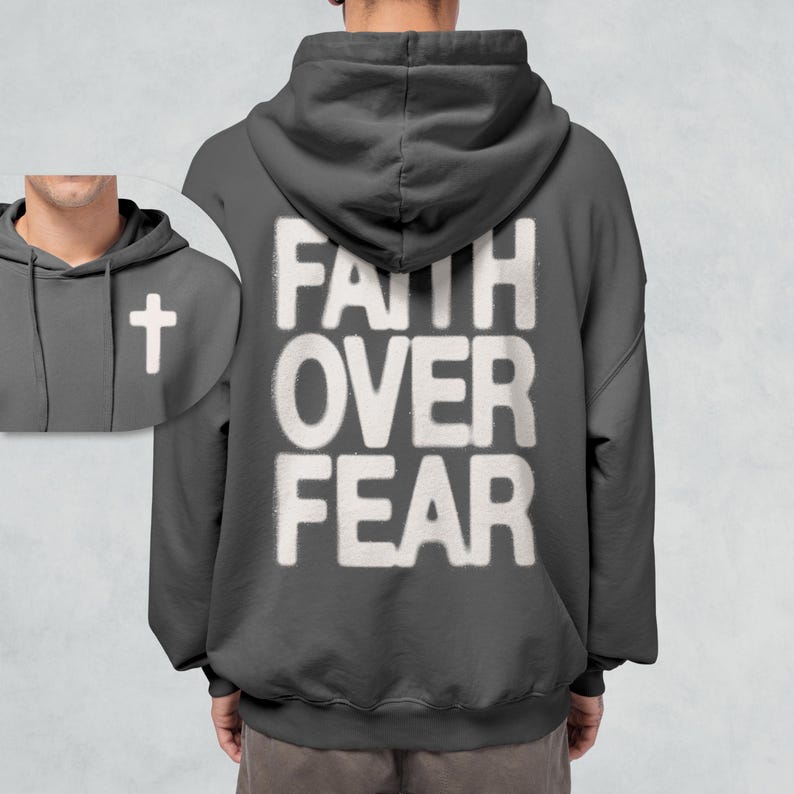 May include: A dark gray hooded sweatshirt with the phrase "FAITH OVER FEAR" printed in white on the back. A small white cross is visible on the front of the sweatshirt.