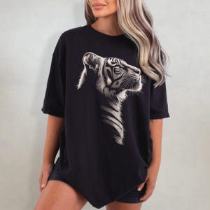 Puede incluir: Una camiseta negra de gran tama&ntilde;o con un estampado gr&aacute;fico de tigre blanco. El tigre est&aacute; mirando hacia la derecha y tiene un dise&ntilde;o detallado.