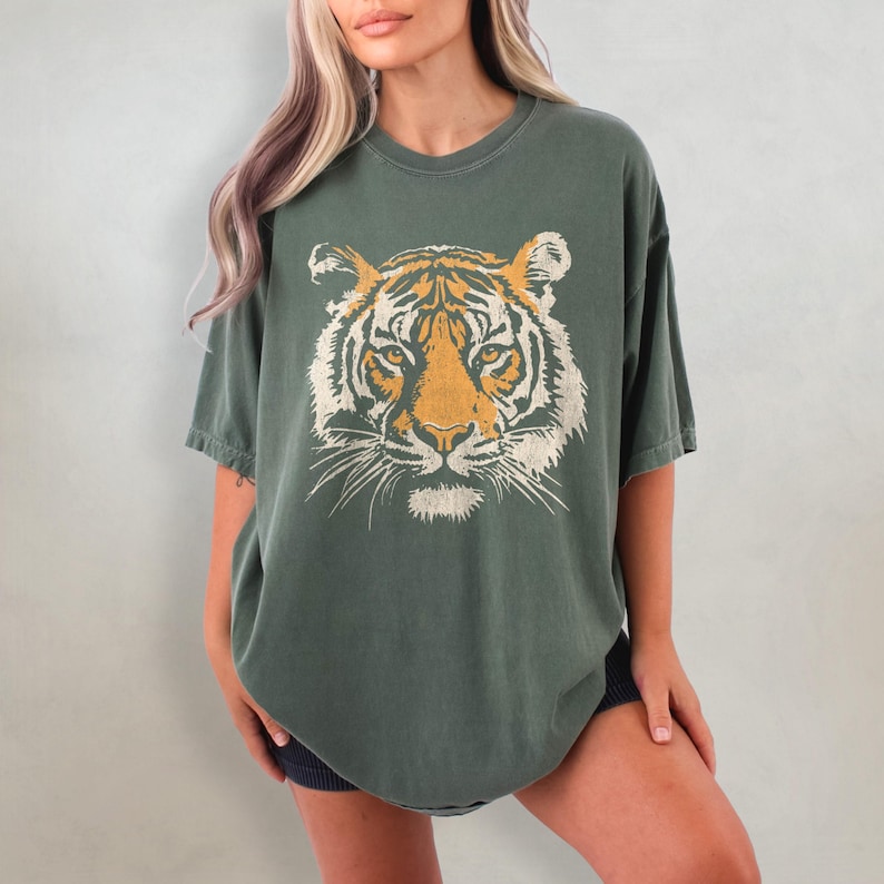 May include: A green oversized t-shirt with a vintage-style tiger face graphic printed on the front.