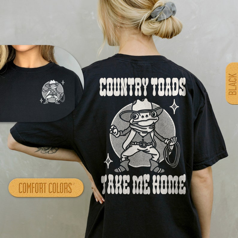 Puede incluir: Camiseta negra con un gr&aacute;fico blanco de una rana de dibujos animados con un sombrero de vaquero y sosteniendo un lazo. El texto "COUNTRY TOADS TAKE ME HOME" est&aacute; impreso en blanco en la camiseta.