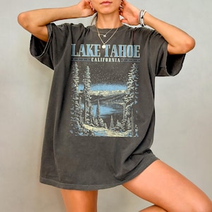 May include: A dark gray oversized t-shirt with a graphic print of a snowy mountain scene and the text "Lake Tahoe, California".