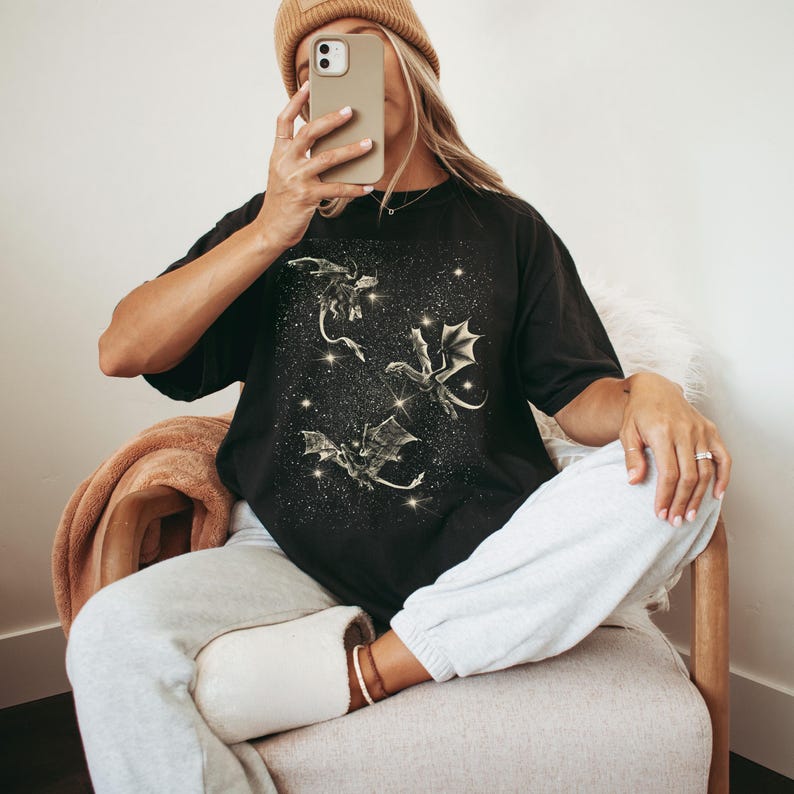 May include: A black t-shirt with a graphic print of three gold dragons flying in a starry sky.