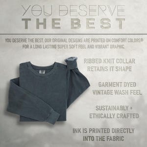 May include: A dark blue long-sleeved t-shirt with a ribbed knit collar. The shirt is garment dyed for a vintage wash feel. The text "YOU DESERVE THE BEST" is printed at the top of the image. The text "RIBBED KNIT COLLAR RETAINS IT SHAPE" is printed below the shirt. The text "GARMENT DYED VINTAGE WASH FEEL" is printed below the collar text. The text "SUSTAINABLY + ETHICALLY CRAFTED" is printed below the vintage wash feel text. The text "INK IS PRINTED DIRECTLY INTO THE FABRIC" is printed at the bottom of the image.