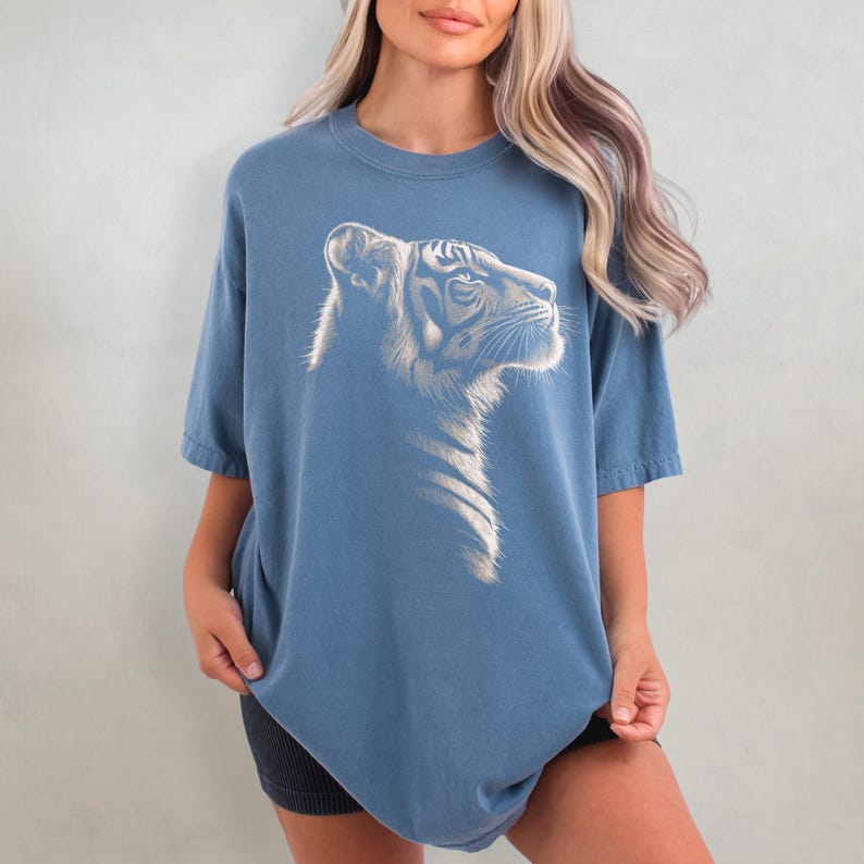 Puede incluir: Una camiseta azul de gran tama&ntilde;o con un gr&aacute;fico blanco de la cabeza de un tigre.