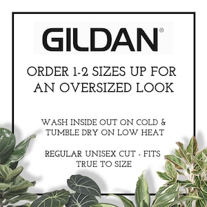 May include: White text on a black background with the brand name "GILDAN" and instructions for sizing and washing Gildan clothing. The text reads: "ORDER 1-2 SIZES UP FOR AN OVERSIZED LOOK. WASH INSIDE OUT ON COLD & TUMBLE DRY ON LOW HEAT. REGULAR UNISEX CUT - FITS TRUE TO SIZE."