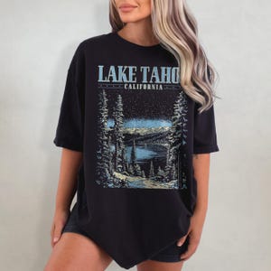 May include: Black oversized t-shirt with a graphic print of a lake and mountains. The text "LAKE TAHOE CALIFORNIA" is printed on the shirt.