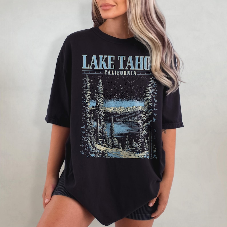 May include: Black oversized t-shirt with a graphic print of a lake and mountains. The text "LAKE TAHOE CALIFORNIA" is printed on the shirt.