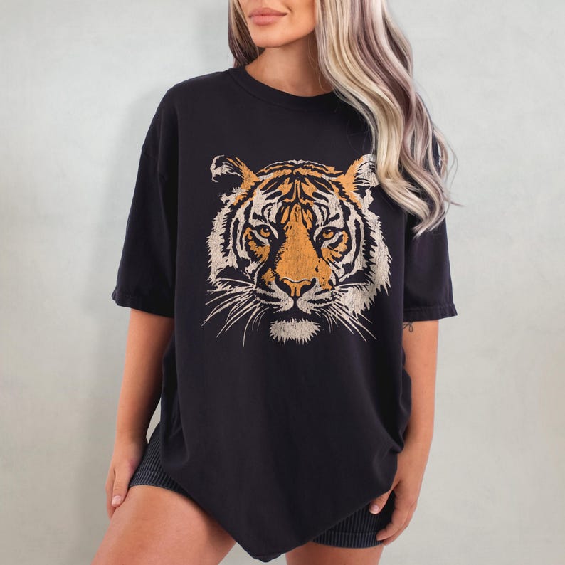 May include: Black oversized t-shirt with a vintage-style tiger face graphic printed on the front.