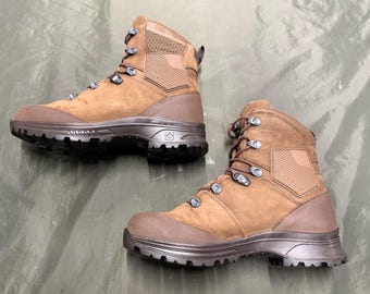 Op de afbeelding: Een paar bruine wandelschoenen met een robuust ontwerp. De schoenen hebben een combinatie van suède en synthetische materialen, metalen veterogen en een dikke, getextureerde zool. Ontworpen voor buitenactiviteiten.
