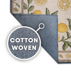 K&ouml;nnte beinhalten: Ein Baumwollteppich mit einem Zitronen- und Bl&auml;ttermuster. Der Teppich hat einen hellbeige Hintergrund mit gelben Zitronen und gr&uuml;nen Bl&auml;ttern. Der Rand des Teppichs ist dunkelblau. Die Worte "COTTON WOVEN" stehen in einem wei&szlig;en Kreis.