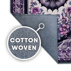 May include: A section of a cotton woven rug with a floral design in shades of purple, black, and cream. The rug's edge is visible, showing a blue backing. The text "COTTON WOVEN" is displayed in a circular inset.