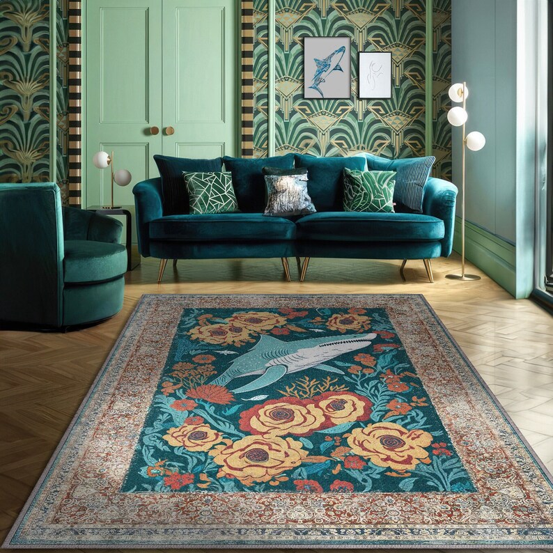 Pu&ograve; includere: Un tappeto turchese con un design floreale e di squali. Il tappeto presenta un'immagine centrale di uno squalo circondato da fiori gialli e arancioni. Il bordo ha un motivo ornato e sbiadito. Il tappeto si trova in un soggiorno con mobili turchesi.