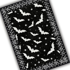 May include: Black rectangular rug with a Halloween theme. The rug features white bats and stars on a black background. The border has a white floral pattern on a black background.