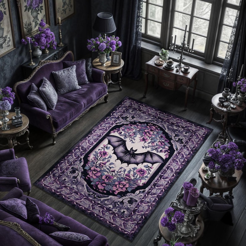 May include: A purple and black area rug with a bat and floral design. The rug features a central oval with a bat illustration surrounded by pink and purple flowers. The border has a decorative pattern, and the rug is placed in a room with purple furniture.
