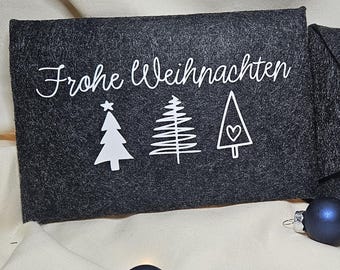 Könnte beinhalten: Zwei dunkelgraue Filz-Weihnachtsumschläge. Einer zeigt den Text "Frohe Weihnachten" mit Baumillustrationen. Der andere hat ein graues Herz mit einem schwarzen Knopf. Blaue Kugeln sind im Vordergrund.