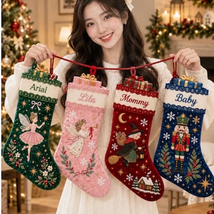 May include: Four velvet Christmas stockings with embroidered designs and names. The green stocking features a fairy, the pink one an angel, the red one a witch, and the blue one a nutcracker. Each stocking has a gift box on top and a red hanging cord.