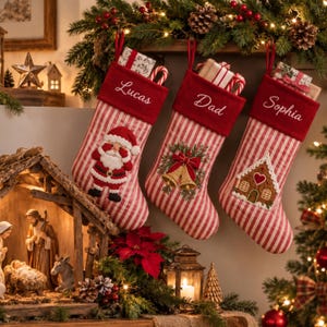 Può includere: Tre calze natalizie a righe rosse e bianche con risvolti in velluto rosso che riportano i nomi ricamati Lucas, Dad e Sophia. Ogni calza presenta un'applicazione unica: un Babbo Natale, campane dorate con agrifoglio e una casetta di pan di zenzero.