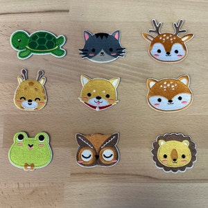 Może przedstawiać: Zestaw dziesięciu haftowanych naszywek do prasowania z różnymi zwierzętami, w tym żółwiem, kotem, jeleniem, żyrafą, psem, sową i lwem. Naszywki są w stylu kreskówkowym i mają żywe kolory.