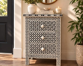 May include: A rectangular three-drawer chest featuring a black and white geometric floral pattern across the front and sides. The chest has three white, flower-shaped knobs and a flat top surface. The frame is constructed with a repeating circular motif.