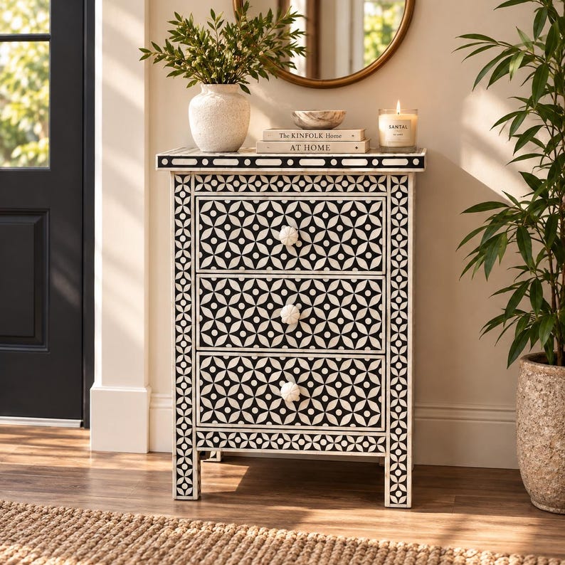 May include: A rectangular three-drawer chest featuring a black and white geometric floral pattern across the front and sides. The chest has three white, flower-shaped knobs and a flat top surface. The frame is constructed with a repeating circular motif.