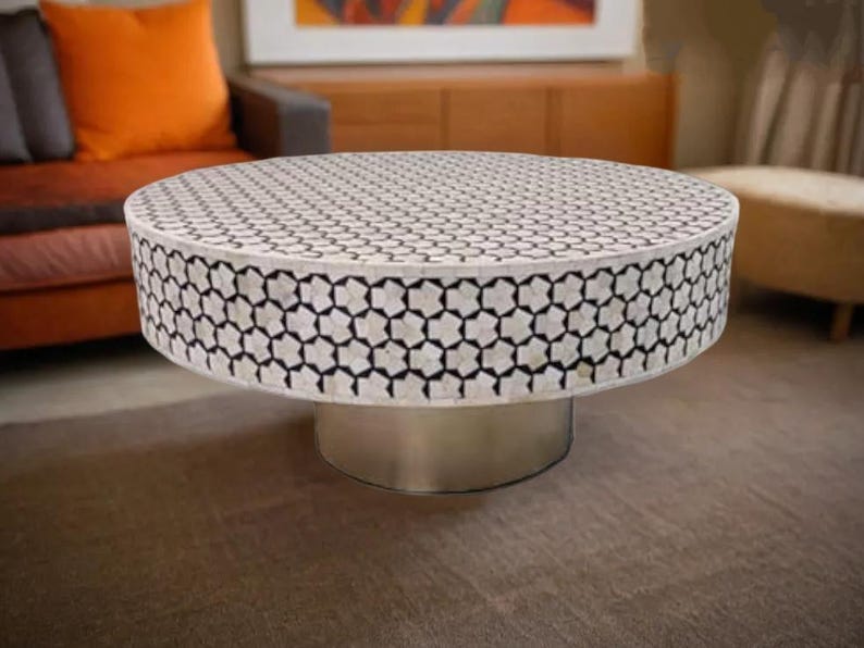 May include: A round, white coffee table with a black and white geometric pattern on the top. The table has a silver base.