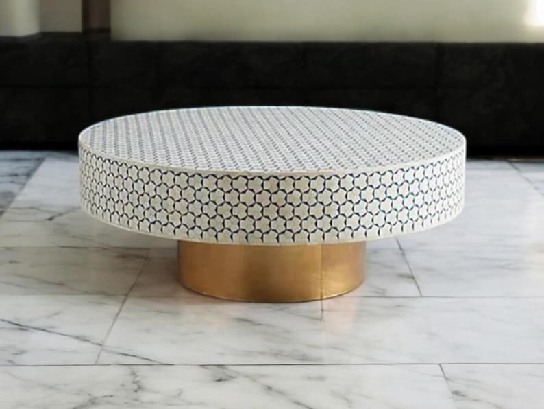 May include: A round coffee table with a white and blue geometric pattern on the top and a gold base.