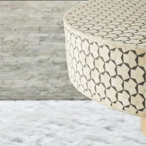 May include: A round, white table top with a black geometric pattern. The table has a gold base.
