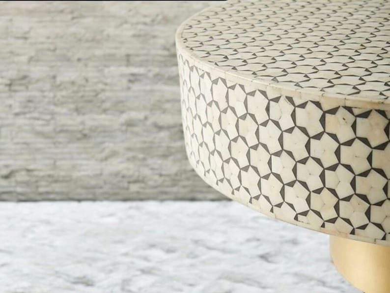 May include: A round, white table top with a black geometric pattern. The table has a gold base.