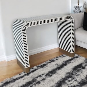 Könnte beinhalten: Ein schwarz-weiß gestreiftes Konsolentisch mit einem geschwungenen Design und Messingakzenten. Der Tisch ist aus Knocheninlay gefertigt und hat einen modernen Stil.