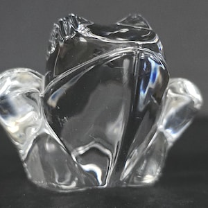 May include: A clear glass rose-shaped ornament. The glass is shaped to look like a blooming rose, with detailed petals and a textured surface. The ornament is designed to stand upright and is suitable for display.
